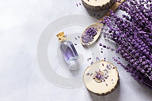Glass bottle of Lavender essential oil with dried lavender flowers and seeds on white table