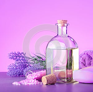 Glass bottle of lavender essential oil with fresh lavender flowers, sea salt, soap and towel