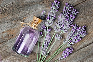 Glass bottle of Lavender essential oil with fresh lavender flowers on wooden rustic table