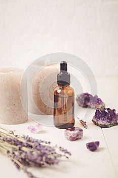 Glass bottle of Lavender essential oil with lavender flowers and candles and amethyst crystals