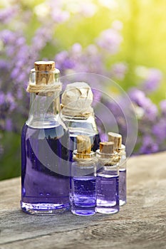 Glass bottle of Lavender essential oil on wood table and flowers field. Lavendula oleum photo