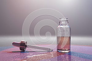 Glass bottle with liquid and godlen medicine dropper on glass background