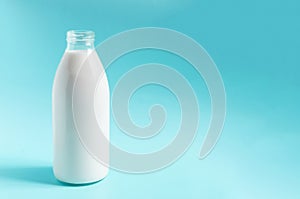 A glass bottle with milk on a blue background. A liter of milk in a glass bottle on a colored background