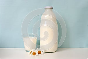 Glass and bottle of milk, on blue background. Natural food.