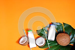 Glass bottle of milk or yogurt on blue napkin onorange background with coconut aside