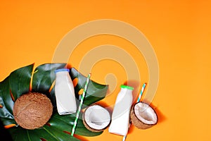 Glass bottle of milk or yogurt on blue napkin onorange background with coconut aside