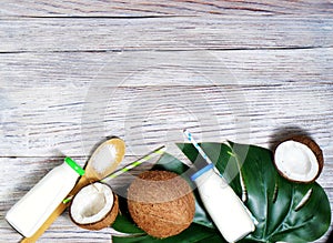 Glass bottle of milk or yogurt on blue napkin on white wooden table with coconut aside