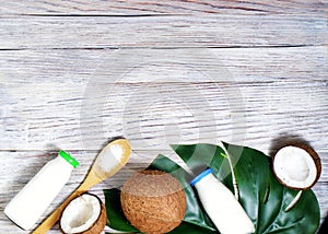 Glass bottle of milk or yogurt on blue napkin on white wooden table with coconut aside