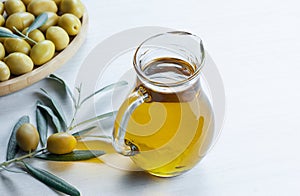 Glass bottle of olive oil and olive tree branch, raw turkish green olive seeds