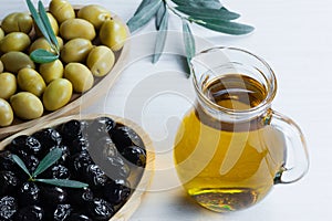 Glass bottle of olive oil and olive tree branch, raw turkish green olive seeds