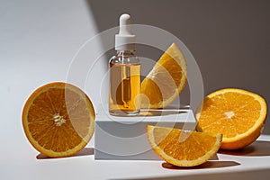 Glass bottle with an orange oil dropper for skin, hair. Packaging with serum on white background in rays of sunlight