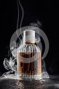 Glass bottle of perfume with a smoke on black background