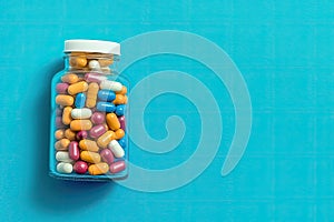 Glass Bottle of Pills is surrounded by a pile of colorful pills