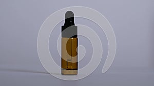 A glass bottle with a pipette stands on a white background.