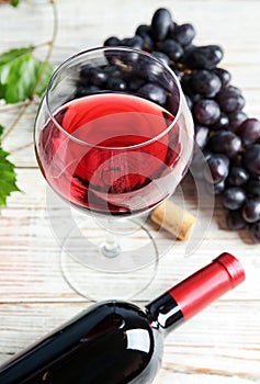 Glass and bottle of red wine with fresh ripe juicy grapes