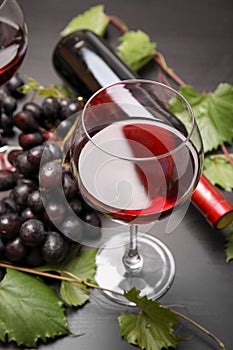 Glass and bottle of red wine and fresh ripe juicy grapes