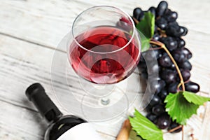 Glass and bottle of red wine with fresh ripe juicy grapes