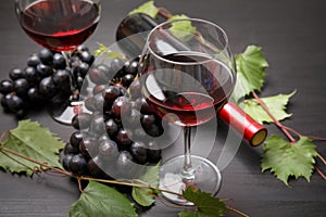 Glass and bottle of red wine and fresh ripe juicy grapes table