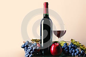 Glass and bottle of red wine with grapes and apples. Red wine on a light background