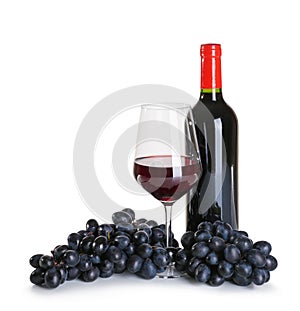 Glass and bottle of red wine with ripe grapes on white background