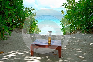 Glass bottle of refreshing bewerage on the table with ocean view on background