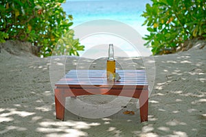 Glass bottle of refreshing bewerage on the table with ocean view on background photo