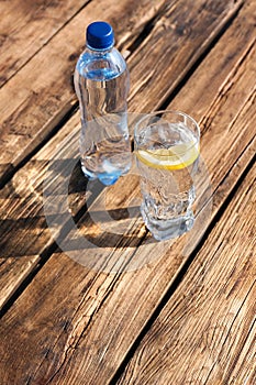 Glass and bottle of refreshing drink for hot summer day on wooden table