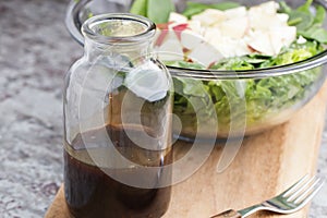 a glass bottle with salad dressing consisting of balsamic vinegar, honey and olive oil