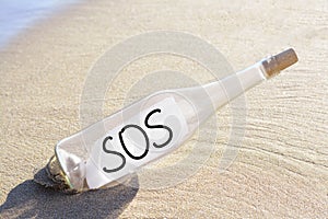 Glass bottle with SOS message on sand near sea