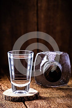 Glass and bottle of strong distilled alcohol, with space for text, black background. Image for pug or bar