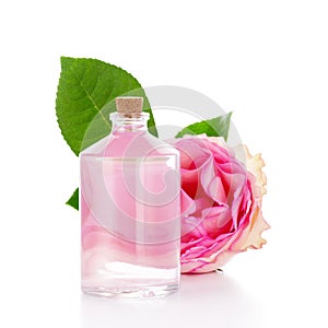 Glass bottle with transparent liquid, pink rose and green leaf