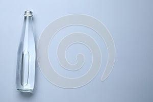 Glass bottle with water on white background, top view. Space for text