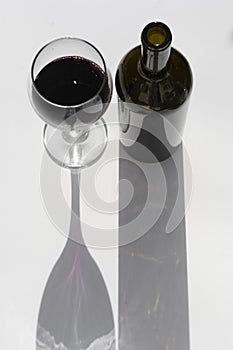 Glass and bottle of wine with dark shadows isolated on a white background