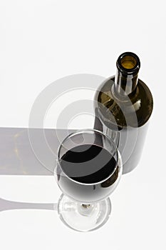 Glass and bottle of wine with dark shadows isolated on a white background