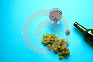 Glass, bottle of wine, green grapes on a blue background