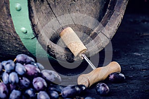 Glass and bottle of wine on a wooden barrel. Burnt, black wooden background. Vintage. Copyspace for a text. Grapes and green vine.