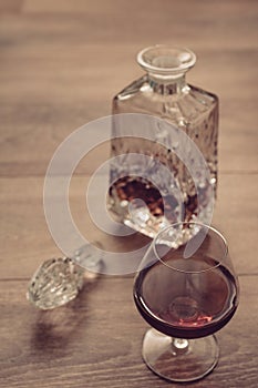 Glass bottle and wineglass with cognac on wooden plank surface