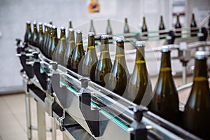 Glass bottles on the automatic conveyor line at the champagne or wine factory. Plant for bottling alcoholic beverages.