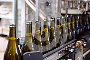 Glass bottles on the automatic conveyor line at the champagne or wine factory. Plant for bottling alcoholic beverages.