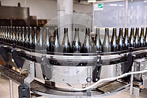 Glass bottles on the automatic conveyor line at the champagne or wine factory. Plant for bottling alcoholic beverages.