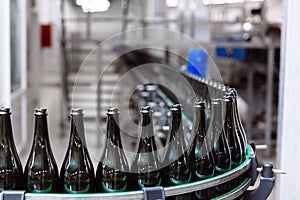 Glass bottles on the automatic conveyor line at the champagne or wine factory. Plant for bottling alcoholic beverages.