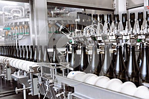 Glass bottles on the automatic conveyor line at the champagne or wine factory. Plant for bottling alcoholic beverages.