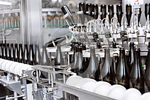 Glass bottles on the automatic conveyor line at the champagne or wine factory. Plant for bottling alcoholic beverages.