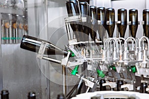 Glass bottles on the automatic conveyor line at the champagne or wine factory. Plant for bottling alcoholic beverages.