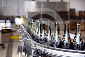 Glass bottles on the automatic conveyor line at the champagne or wine factory. Plant for bottling alcoholic beverages.