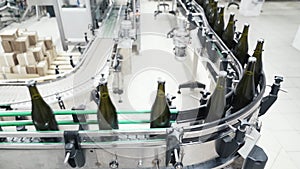 Glass bottles on the automatic conveyor line at the champagne or wine factory. Plant for bottling alcoholic beverages.