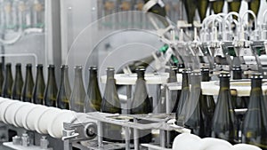 Glass bottles on the automatic conveyor line at the champagne or wine factory. Plant for bottling alcoholic beverages.