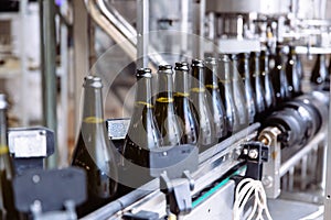 Glass bottles on the automatic conveyor line at the champagne or wine factory. Plant for bottling alcoholic beverages.