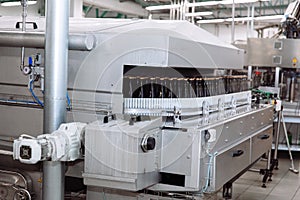 Glass bottles on the automatic conveyor line at the champagne or wine factory. Plant for bottling alcoholic beverages.