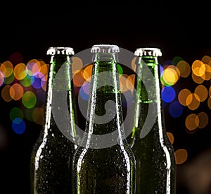 Glass bottles of beer on bar lights background